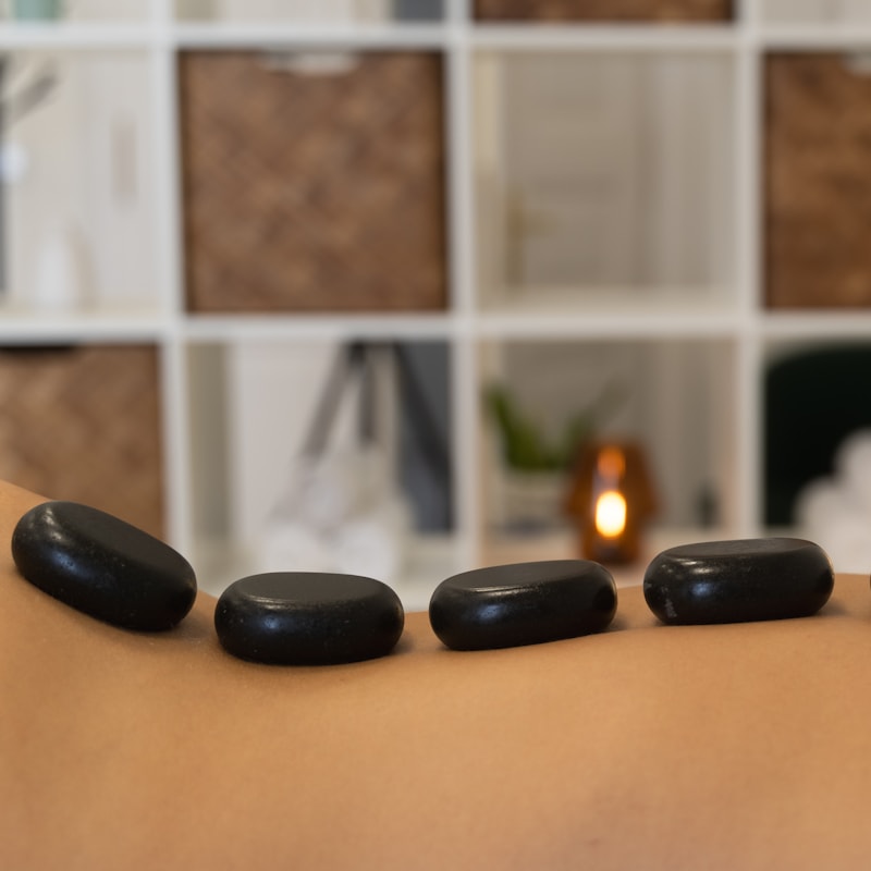 Batu hangat ditata di punggung klien saat pijat hotstone